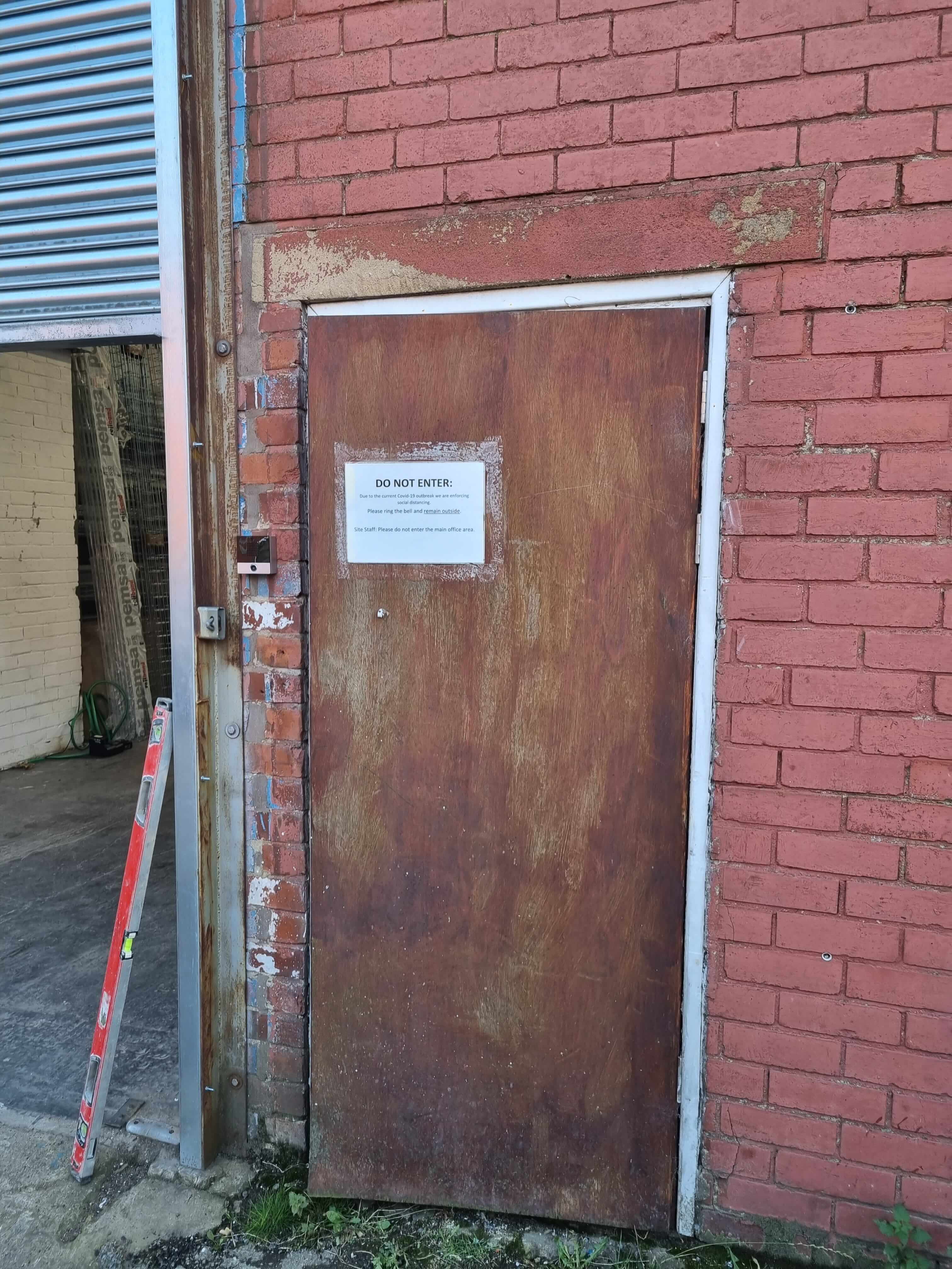 Old brown door between red brick walls