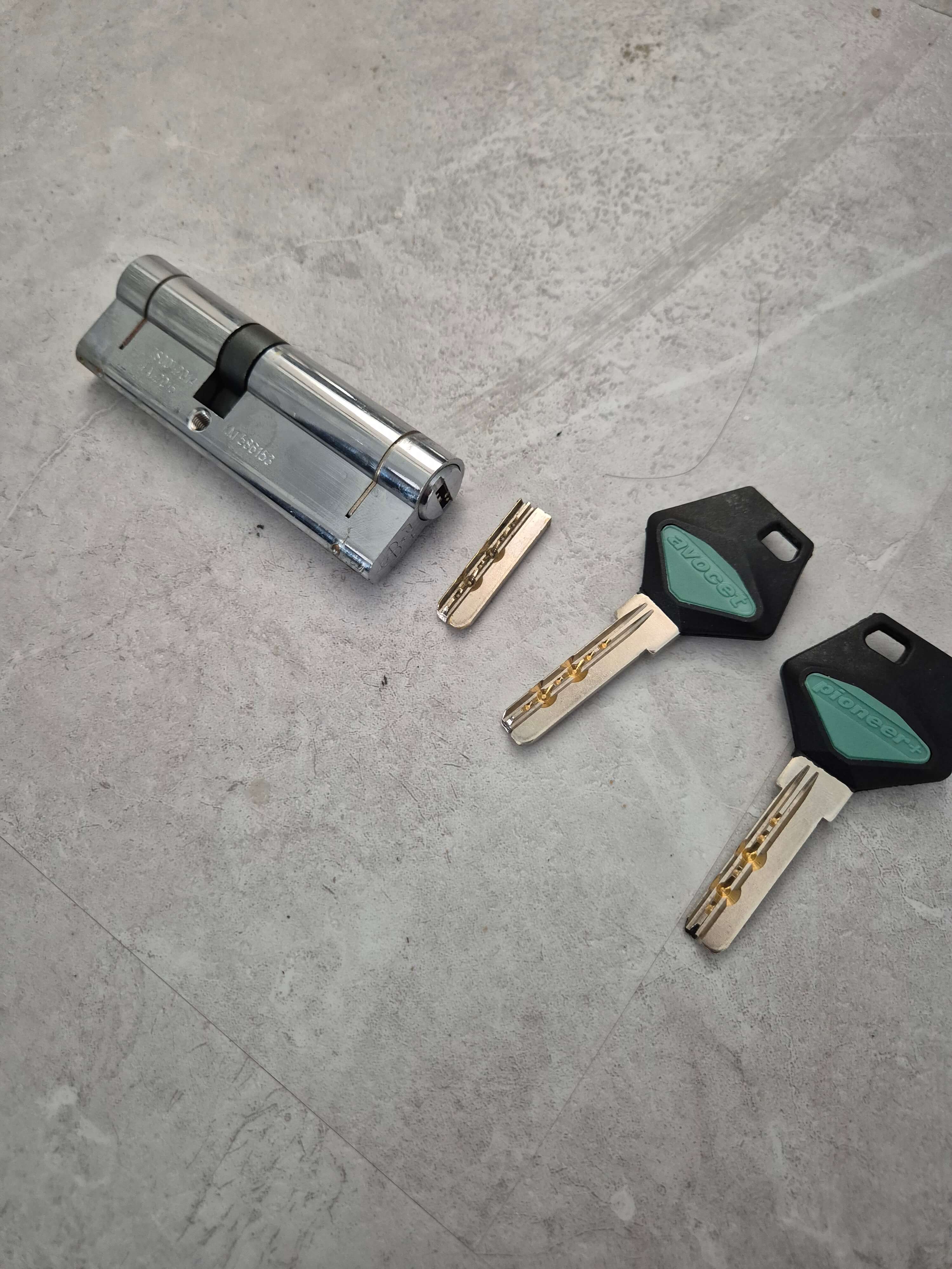 Pioneer chrome euro cylinder laid on marble service showing broken extracted key and 2 spare keys with black and green key tops.