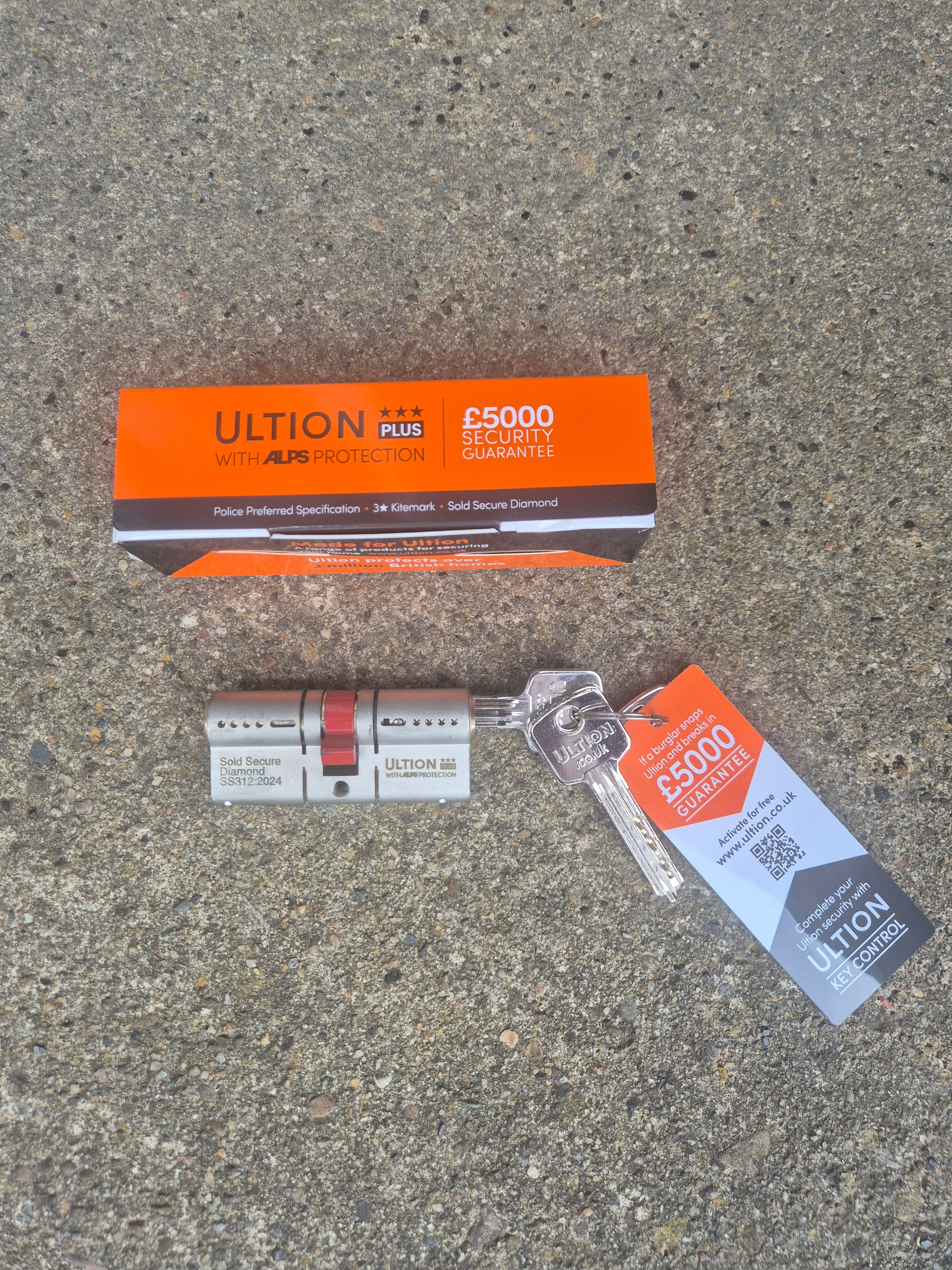 Alps anti snap lock with box, keys and key tag laid on concreate floor