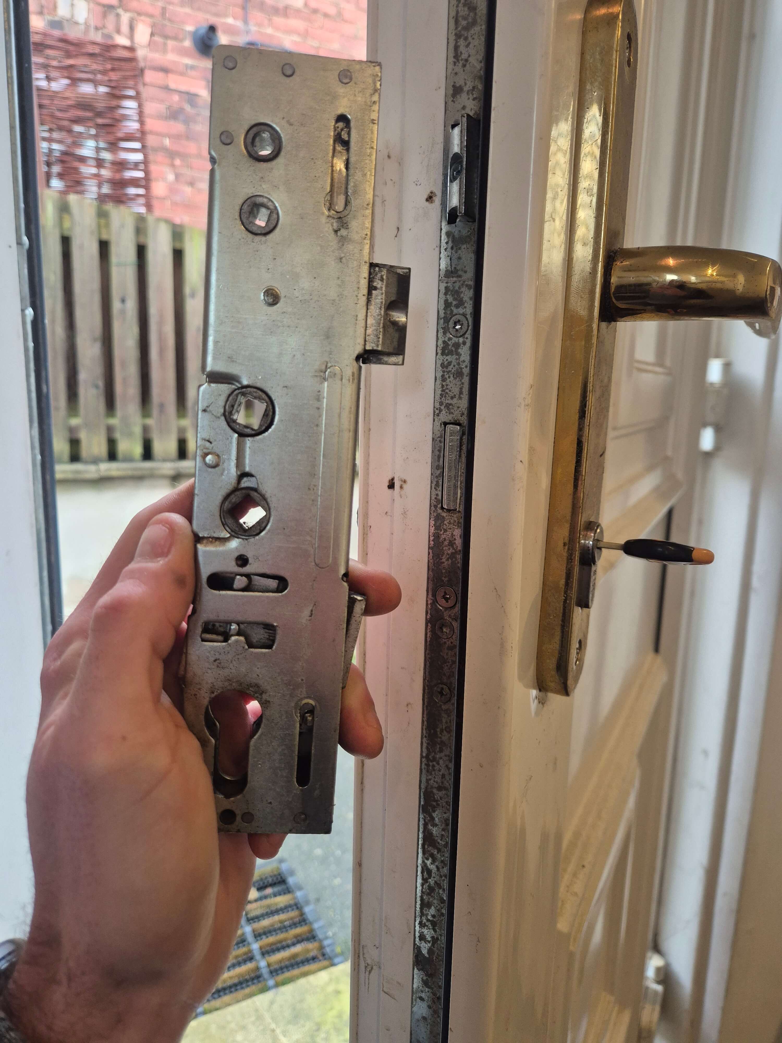 Broken Lockmaster gearbox being held up in infront of repaired white upvc door