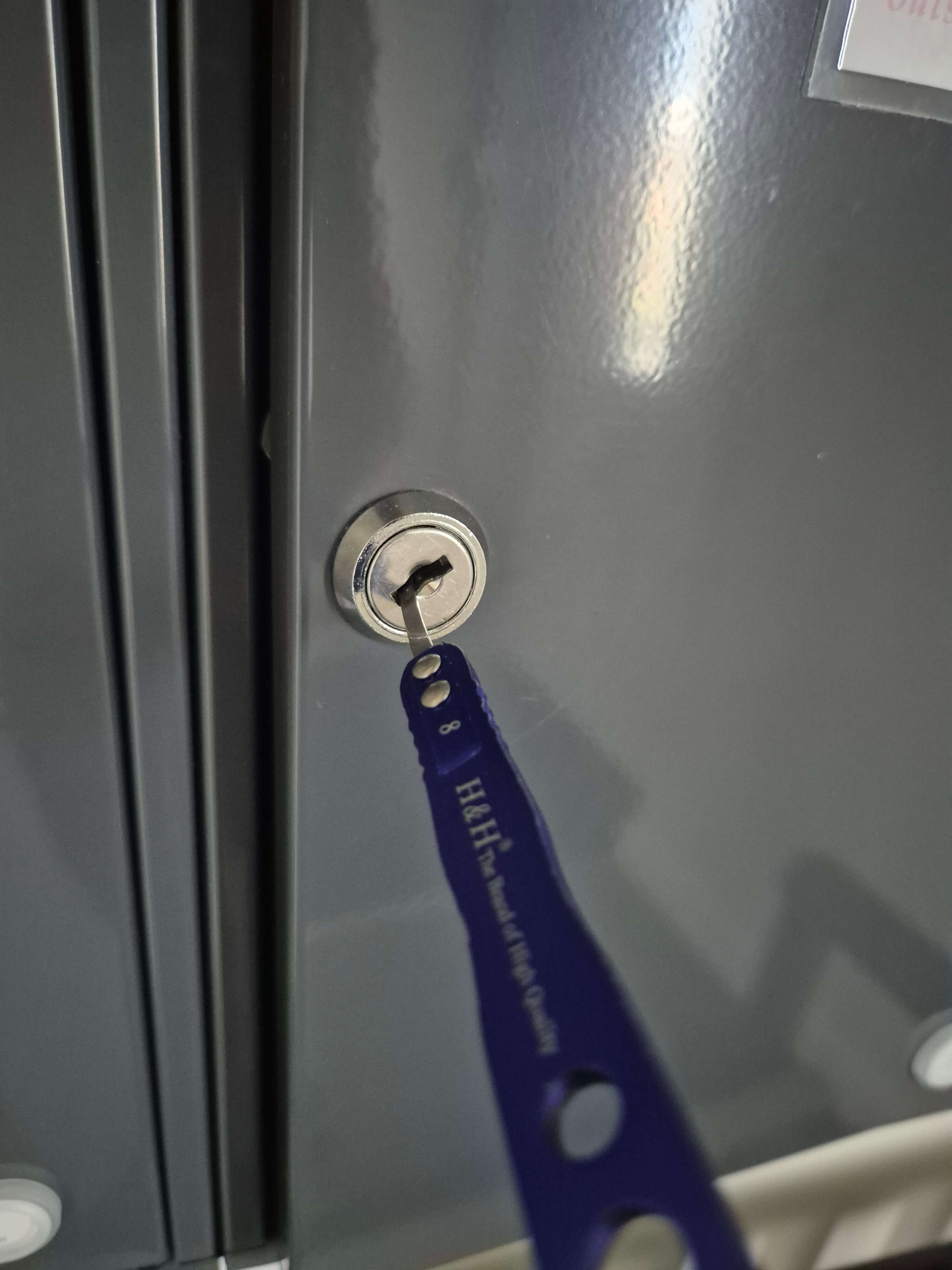 Blue lock pick inside post box lock fitted to grey mailbox 