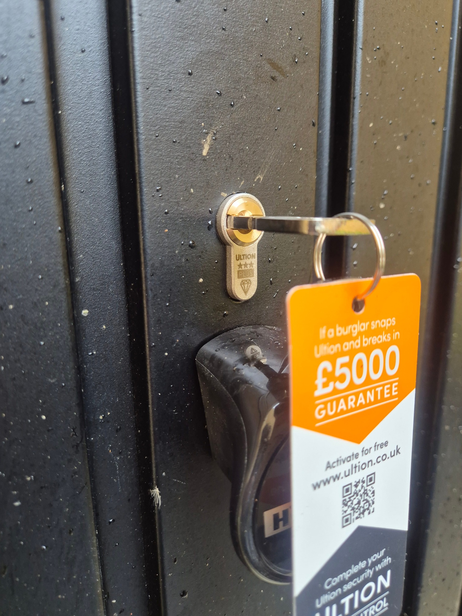 Anti snap lock fitted to black garage door showing orange key tag and key