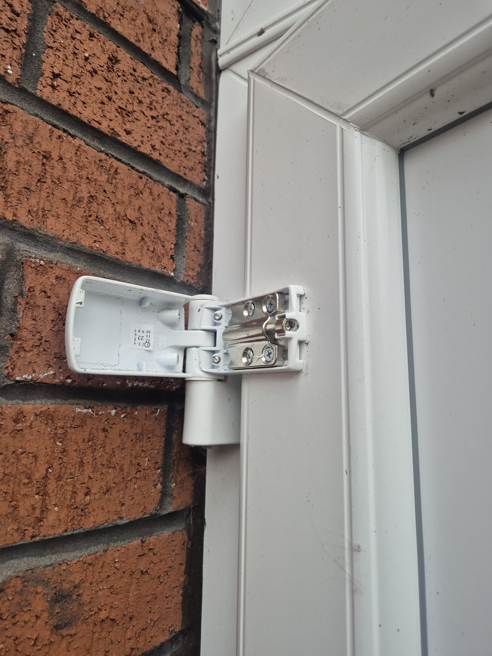 White upvc door hinge on white door with adjuster cover swung open
