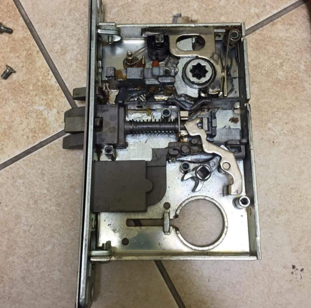 Commercial Assa door lock repaired in Leeds with cover removed showing internals against a tile background  