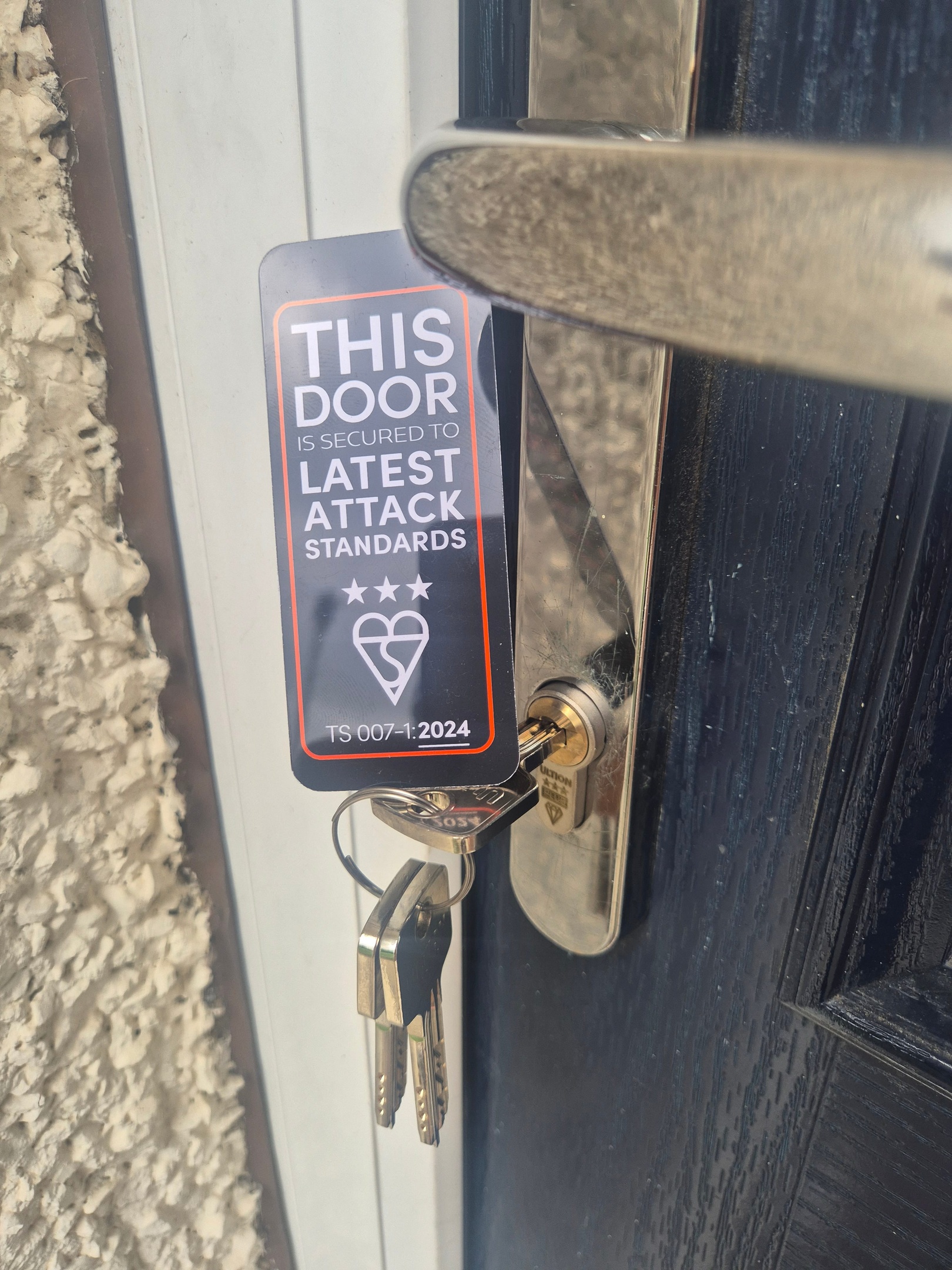 3 star ALPS lock fitted to blue composite door with chrome door handle dispalying tag with latest lock attack standards card